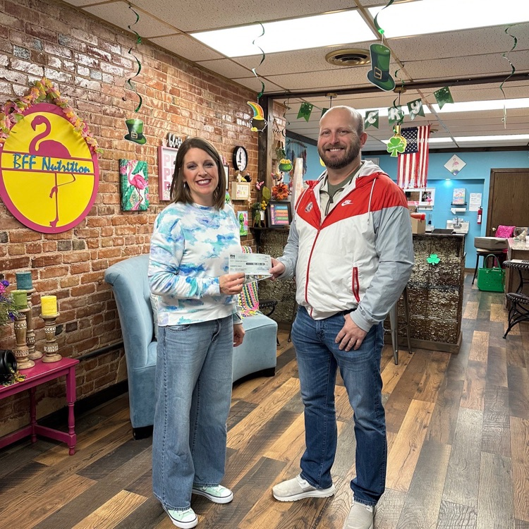 photo of 2 adults. Ms Gould, Boho, presents a check to Cherokee Superintendent Mr Schanbacher on Match 12, 2026  