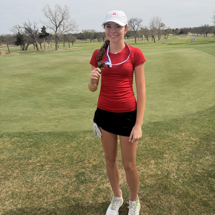 female student on a golf course holding a first place medal