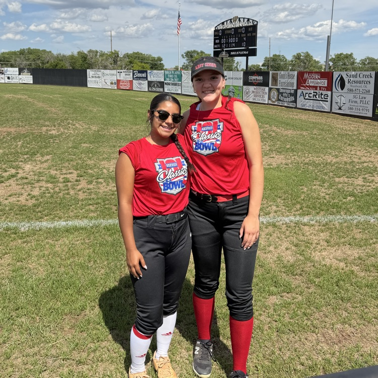 photo of 2 female students on a softball field during the k201 classic bowl softball game  