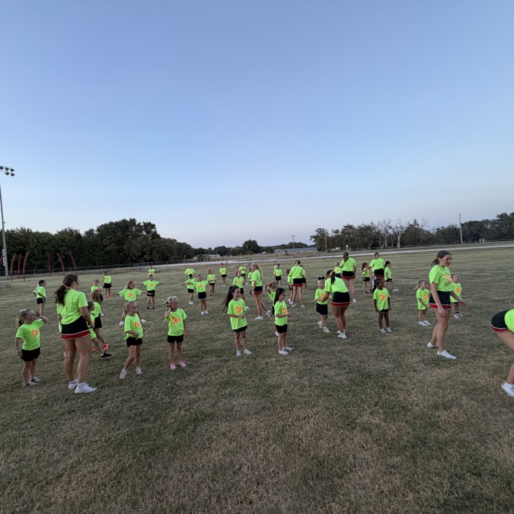 group of students standing on a grassy field. working on a cheer