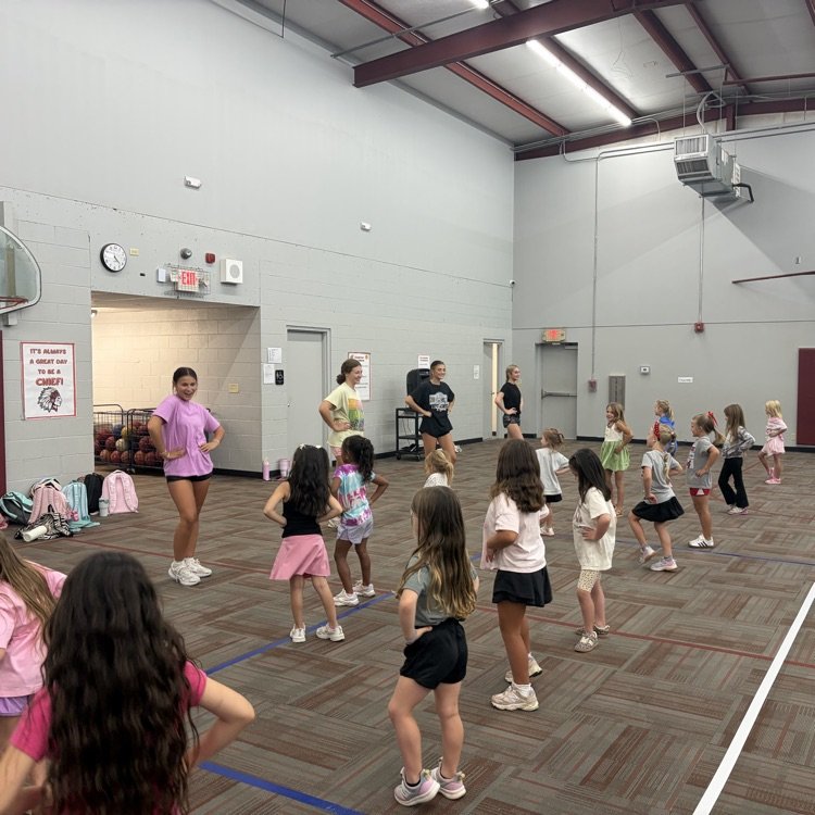 group of students in a gym with carpet. working on a cheer