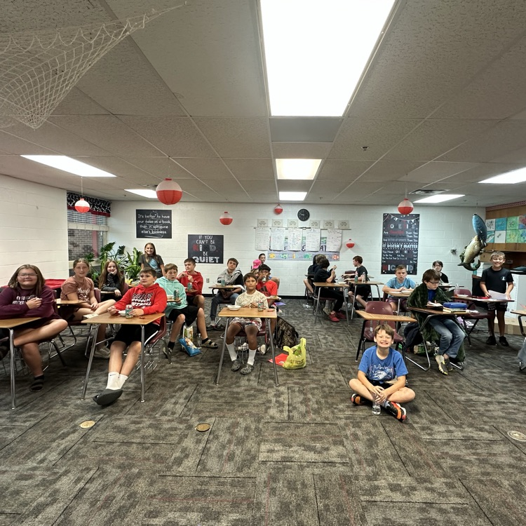 photo of a classroom with students on the floor and at desks