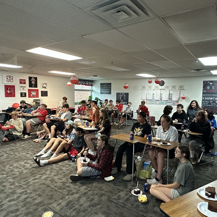 photo of a classroom with students on the floor and at desks