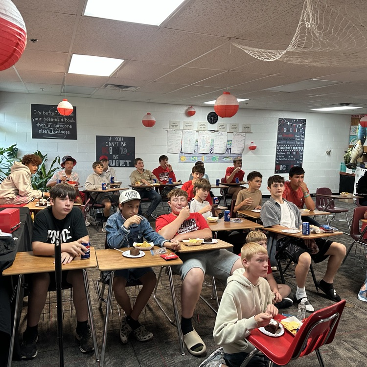 photo of a classroom with students on the floor and at desks