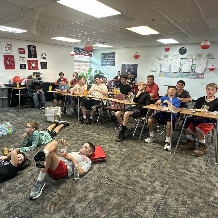 photo of a classroom with students on the floor and at desks