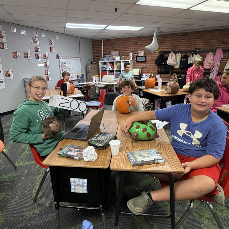 Group of students in a classroom at desks with decorated pumpkins.