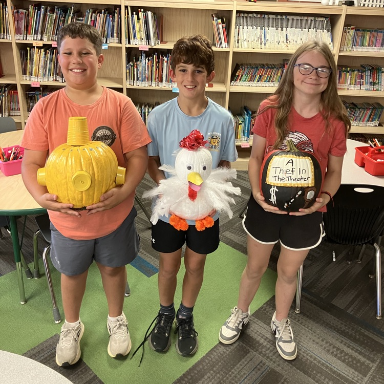 Group of students in a classroom with decorated pumpkins.