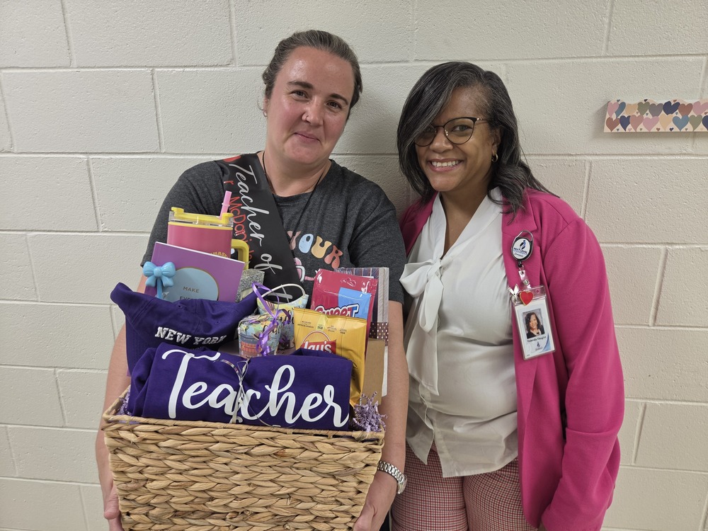 teacher of the year holding a basket of goodies standing next to the principal