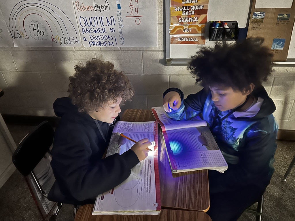2 students reading in the dim lights with flashinlights'