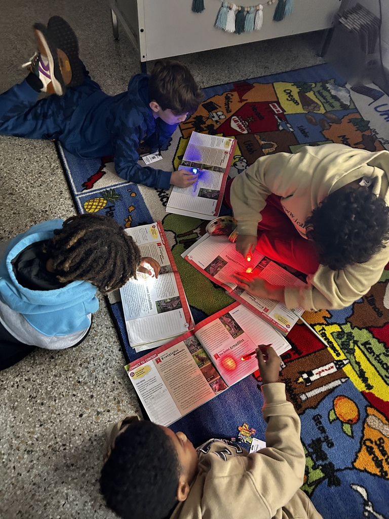 Three students reading with flashlights
