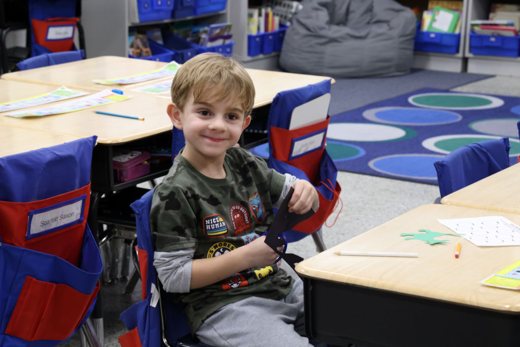 boy smiling and cutting paper