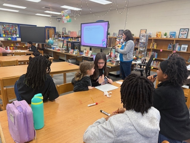 Students at tables in the library working together for the Battle of the Books