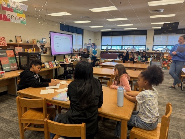 Students at tables in the library working together for the Battle of the Books