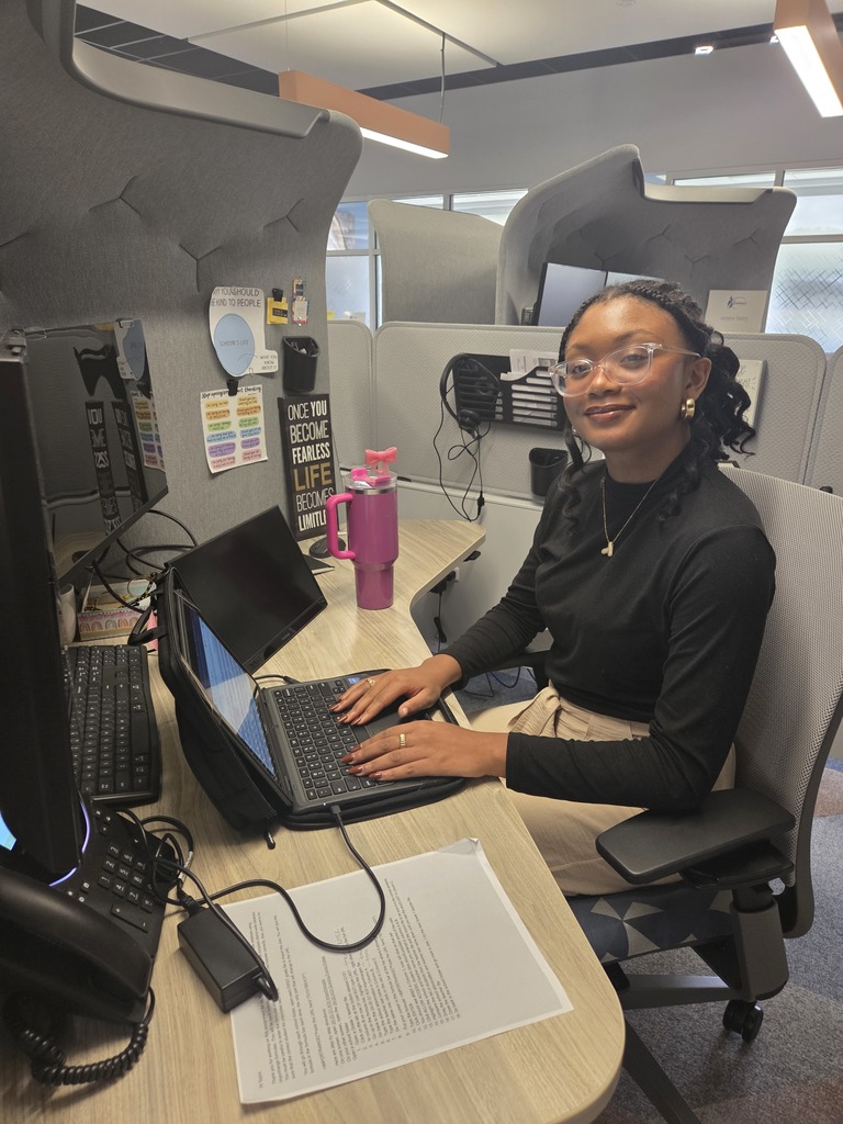 Taylor smiling while working at a computer in an office.