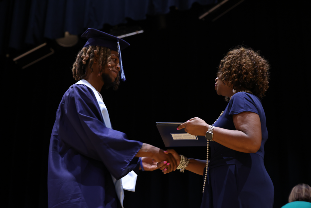 Diploma being handed off to graduate.