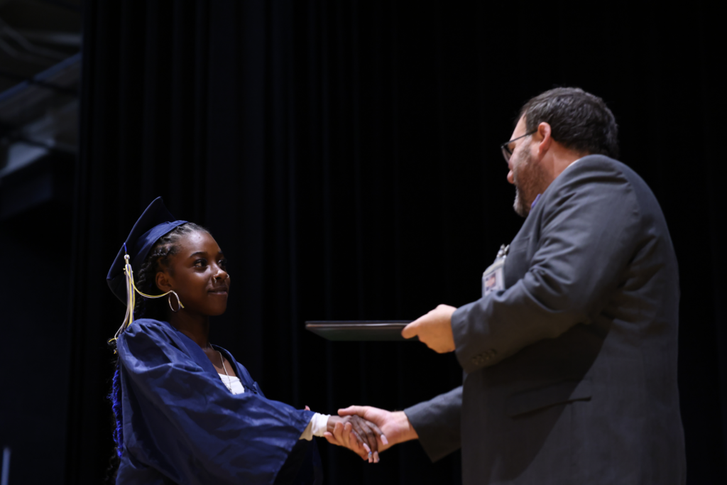 Diploma being handed off to graduate.
