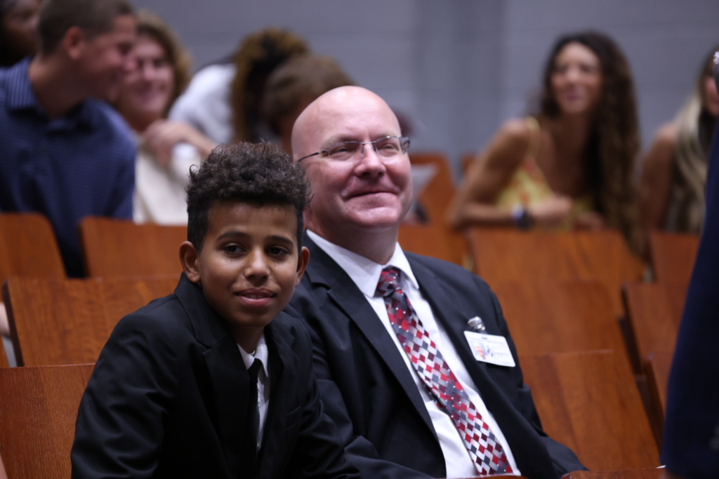 Boy sitting next to an administrator.