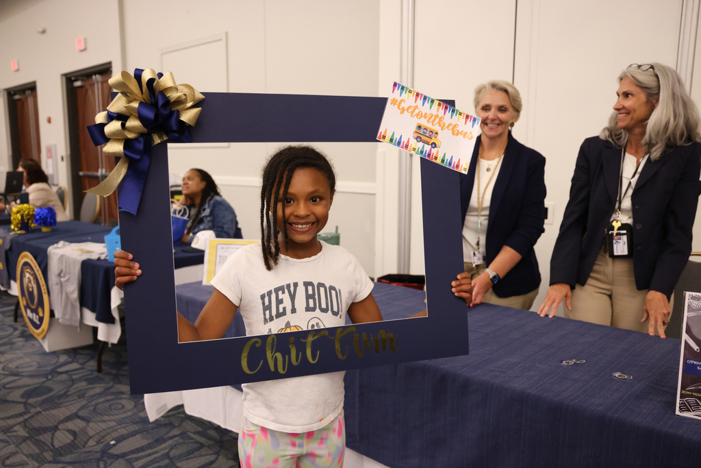 Student holding up photo frame and smiling for picture
