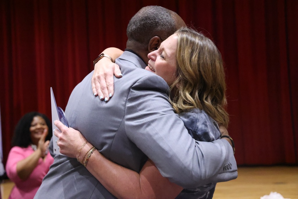 female principal hugging leader