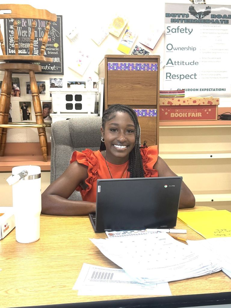 Tyanna smiling at a teacher's desk.