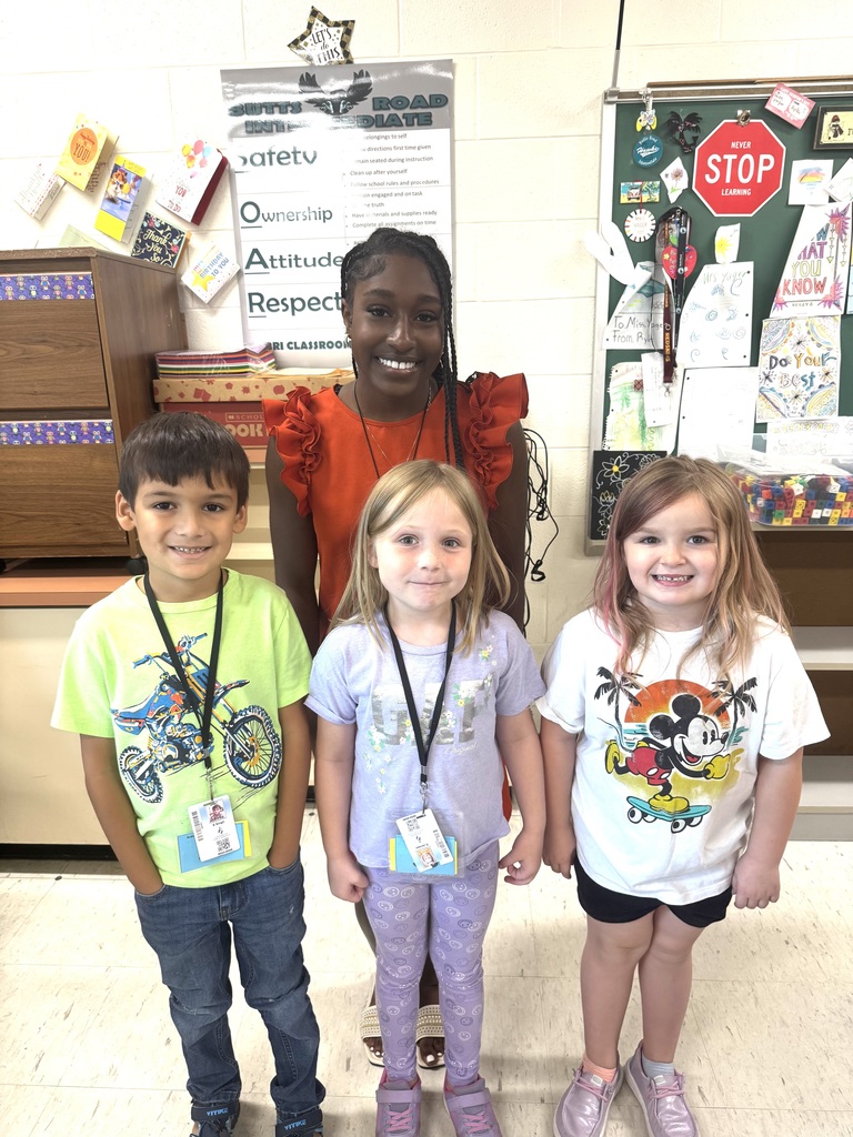 Tyanna smiling with three students in a classroom.