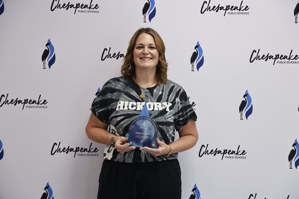 Dr. Donna Weingand holds her award in a picture in front of a white backdrop