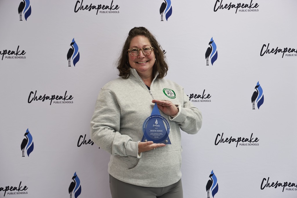Dr. Kristin Rankin holds her award in front of a white backdrop
