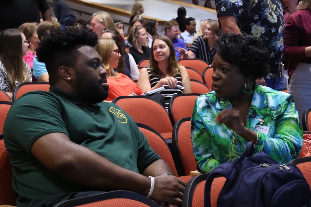two people conversing in auditorium