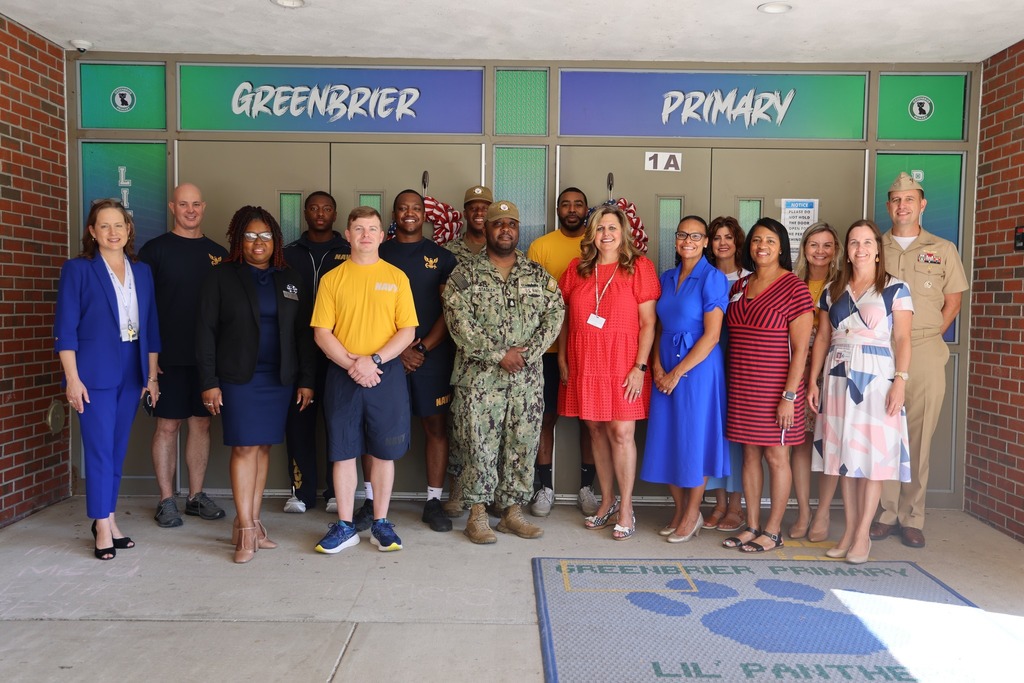 Navy volunteers, principal, and commanding officer smiling in front of Greenbrier Primary.