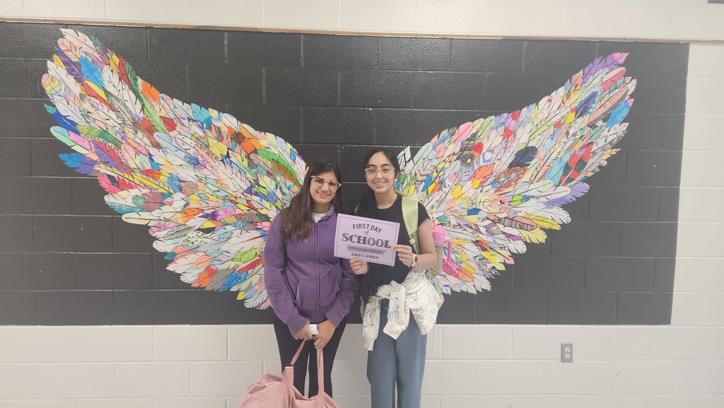 Two students first day of school CPS behind a mural with butterfly wings