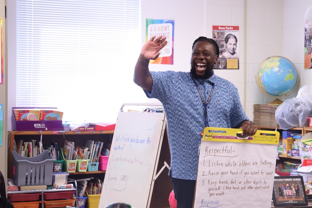 male teacher smiling and waving