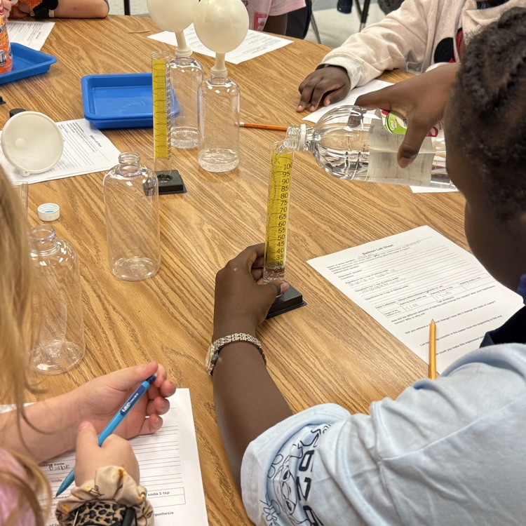 students pouring vinegar into cylinder 
