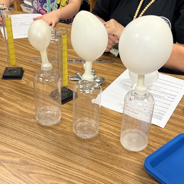 three bottles with vinegar and balloons filled with gas 