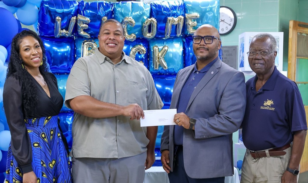 administrator holding check with two males and a female on either side