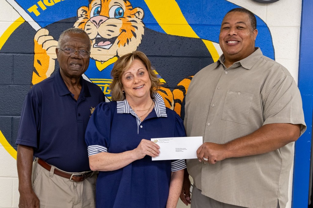administrator holding check with two males on either side