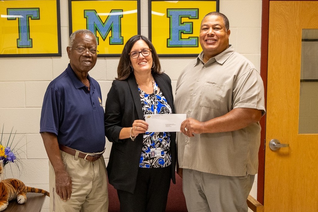 administrator holding check with two males on either side