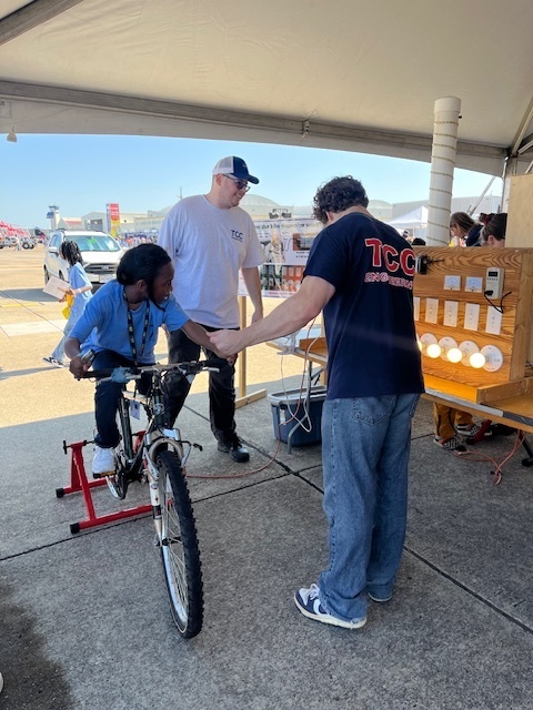 student on bike making light bulbs light up