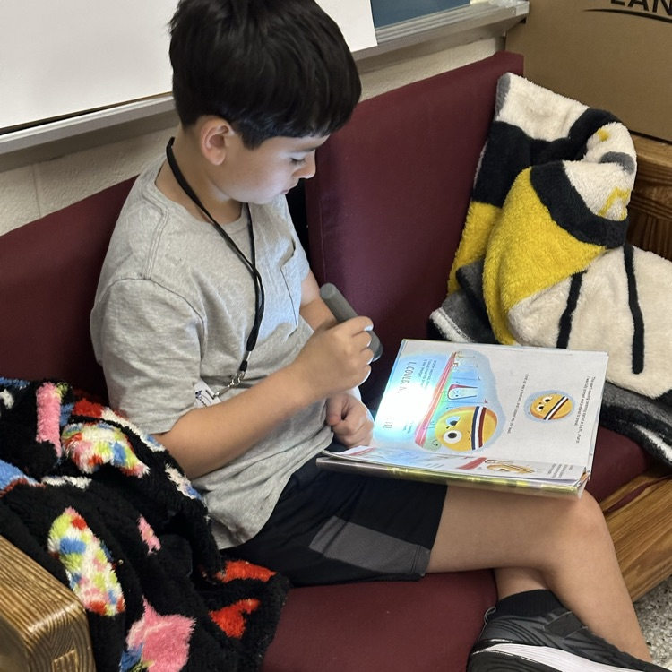 student reading with flashlight on couch 