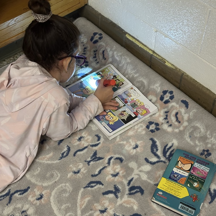 student reading with flashlight on carpet