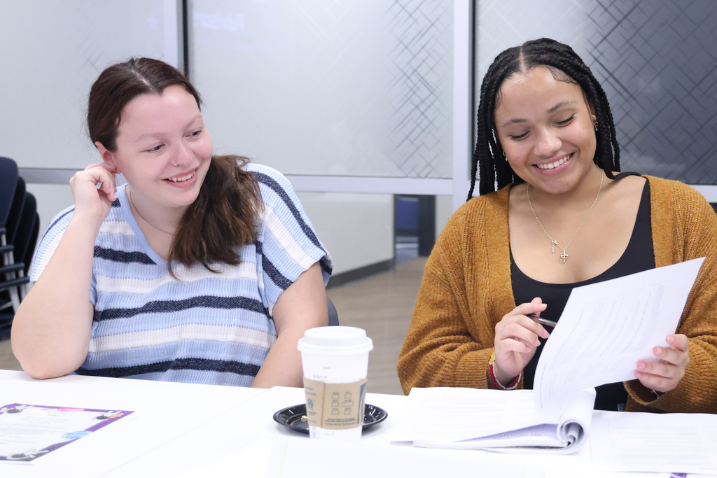 two student leaders smiling and looking at pages