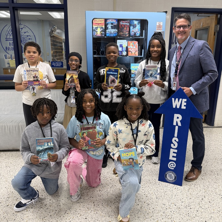 5th graders with books by book machine with Mr. Triolet