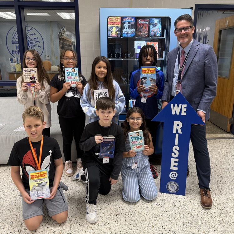 4th Graders with books by book vending machine with Mr. Triolet