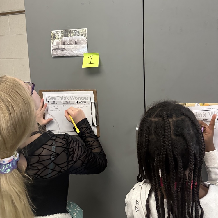 students looking at picture and recording answers on paper