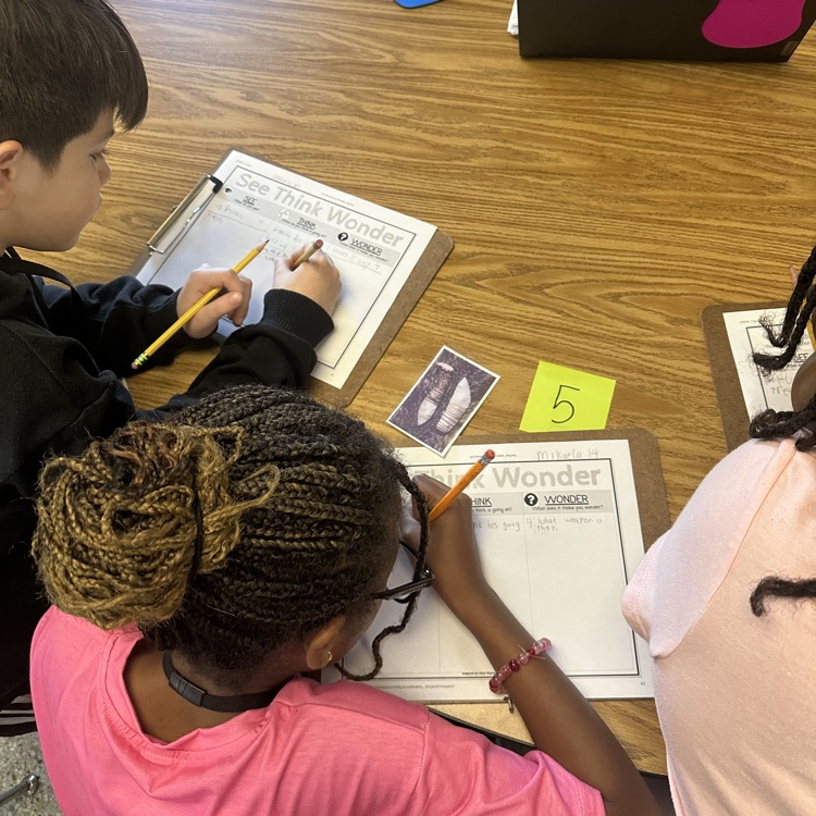 students looking at picture and recording answers on paper