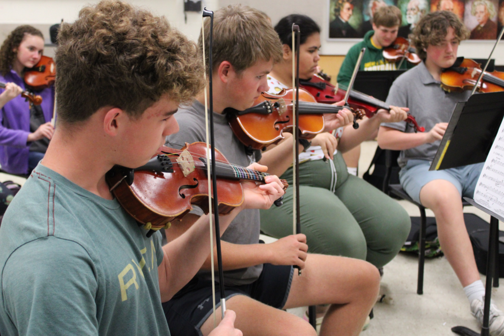 3 students playing violins