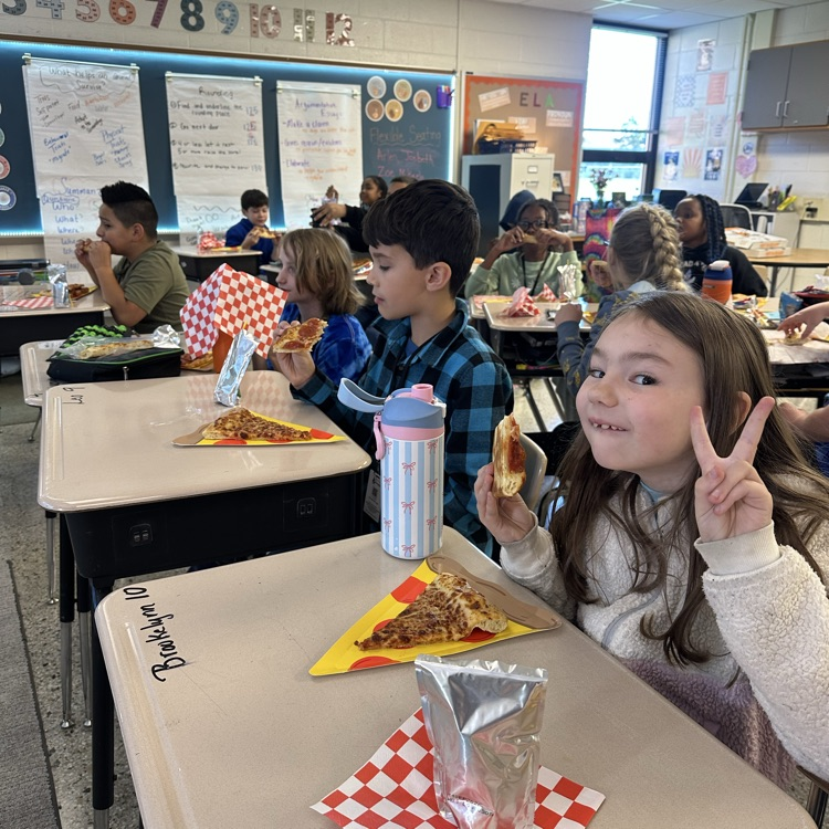 students at desks eating pizza