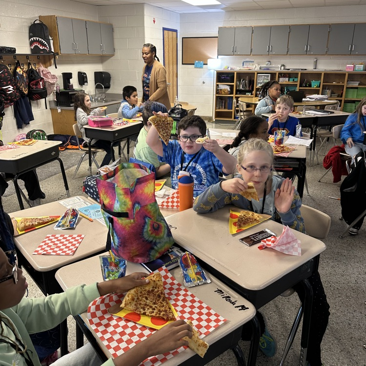 students at desks eating pizza