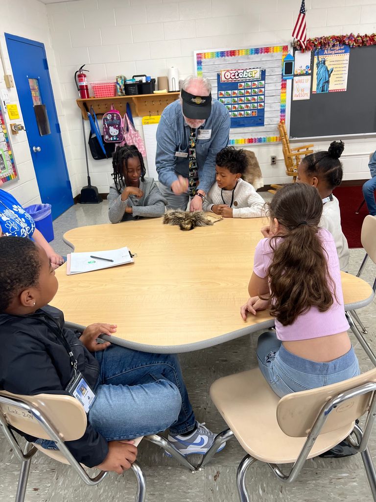 2nd graders with Jamestown presenter using shells to scrap deer fur