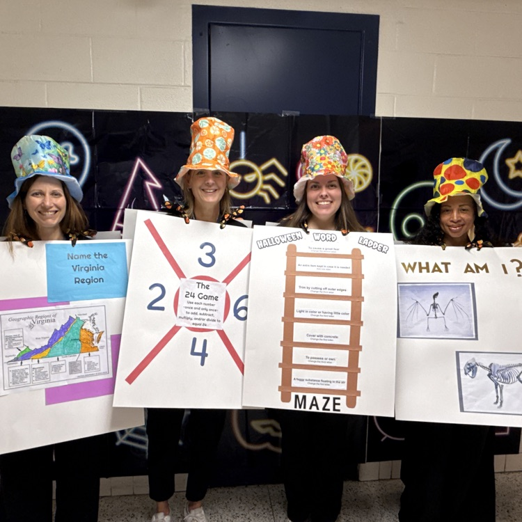 Four teachers dressed with poster board questions and fun hats