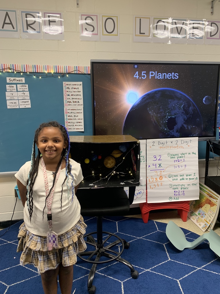 student standing in front of her solar system project